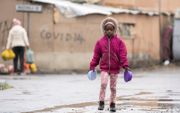 Veel kinderen zijn afhankelijk van school om te kunnen voorzien in hun levensbehoeften met voedselprogramma’s die vanuit scholen worden gecoördineerd. Foto: een kind in Zuid-Afrika op weg naar een voedseluitdeelpunt. beeld ​EPA, Nic Bothma