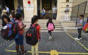 Op de Luigi Einaudischool in Rome moeten de kinderen vanwege de corona-epidemie één voor één naar binnen, met mondkapje. beeld AFP, Vincenzo Pinto