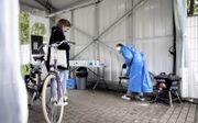 Een GGD-medewerker neemt een coronatest af in Bussum. Door het stijgende aantal besmettingen zijn veel testlocaties overbelast. beeld ANP, Koen van Weel