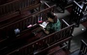Een vrouw leest uit haar Bijbel in een kerk in Chinese stad Wuhan, 2018. beeld AFP, Nicolas Asfouri