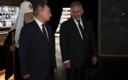 De Russische president Poetin met zijn minister van defensie Shoigu (r). Op de achtergrond de Russisch-Orthodoxe leider Kirill, die grote invloed in het Kremlin heeft. beeld APA, Alexei Nikolsky
