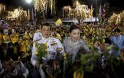 Toeschouwers juichen het Thaise koningspaar toe bij het koninklijk paleis in Bangkok. Als reactie op de protesten blijft de koning langer dan gepland in eigen land. Normaal gesproken woont hij in Duitsland. beeld EPA, Rungroj Yongrit