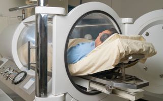 Een man in een cilindervormige machines voor hyperbare zuurstoftherapie. beeld Getty Images