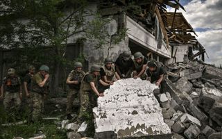 Oekraïense militairen inspecteren een verwoest winkelpand in de buitenwijken van Lysiansk, in de Donbas. beeld AFP, Aris Messinis