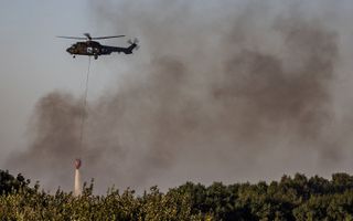 Een blushelikopter van Defensie hielp deze week bij het bestrijden van een brand in het duingebied bij de Brouwersdam. beeld ANP, Jeffrey Groeneweg