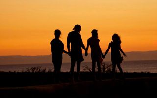 Christelijke opvoeding: een gezin bij een ondergaande zon. beeld Unsplash