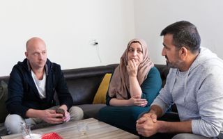 Maatschappelijk werker Jeroen Geertsma (l.) in gesprek met Warshin en zijn vrouw Fatima. beeld RD, Anton Dommerholt