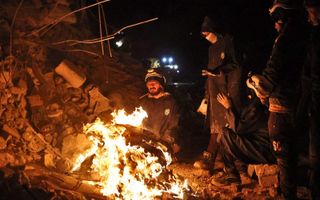 Reddingswerkers in Syrië warmen zich even bij een vuur. beeld AFP, Aaref Watad