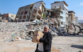 Een man draagt een doos met hulpverleningsproducten in het rampgebied in Turkijke. beeld ANP
