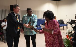 Directeur Rieuwerd Buitenwerf van het Nederlands-Vlaams Bijbelgenootschap en ds. Adu Twumasi van het Ghanees Bijbelgenootschap overhandigen de eerste Twi-Bijbel aan Grace Yeboah. beeld NBG