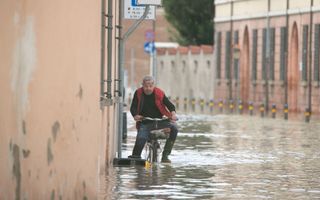 Een man fietst door het water in Lugo, bij Ravenna, Italië. Delen van de stad stonden een meter onder water na het overstromen van de rivieren Senio en Santerno door hevige regenval. beeld EPA, Emanuele Valeri