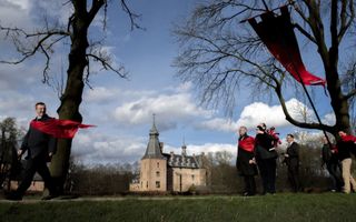 Met hun kenmerkende rode vlaggen lopen mensen van Civitas Christiana een tocht rond kasteel Doorwerth. beeld ANP, Bram Petraeus