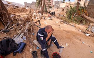 Een hulpverlener moet even bijkomen tijdens zijn werk in de stad Derna. beeld AFP, Karim SAHIB