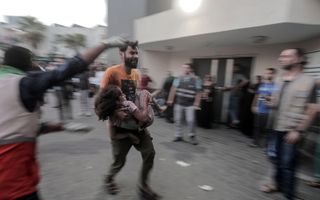 Een Palestijnse man rent met een kind in zijn armen naar het ziekenhuis. beeld EPA