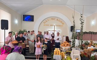 Zo vieren christenen in Oost-Europa dankdag: ze staan voorin de kerk en houden eten vast. Rechts in beeld een deel van de tentoonstelling met kratten en kisten vol levensmiddelen. beeld Gerben Heldoorn