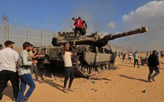 Palestijnen bij een veroverde Israëlische Merkava-tank. Hamas heeft naar eigen zeggen de mythe van het onoverwinnelijke leger doorgeprikt. beeld AFP, Said Khatib