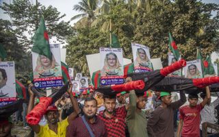 Leden van de Awami Liga houden foto’s omhoog van premier Sjeik Hasina Wazed. De verkiezingen zondag lijken een eenvoudige prooi te worden voor de regeringspartij. beeld EPA, Monirul Alam