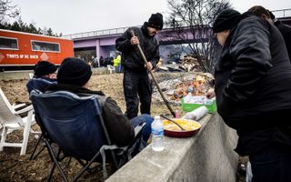 Boeren eten vrijdag een hapje terwijl ze de grensovergang Arendonk tussen België en Nederland blokkeren. beeld ANP, Rob Engelaar