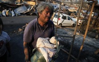 Een man met zijn bezittingen die hij heeft gered nadat bosbranden zijn huis in as legden in Chili. Beeld AFP, Javier TORRES
