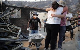 Getroffenen zoeken steun bij elkaar in Chili na verwoestende bosbranden. Zeker 131 mensen kwamen de afgelopen dagen om door het vuur. beeld AFP, Javier Torres