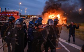 Franse politie bij een brandende vrachtwagen tijdens een boerenprotest tegen belastingen en dalende inkomens in Narbonne op 26 januari 2024. beeld AFP, Ed Jones