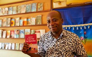 Nicolas Mena in zijn evangelisch boekwinkeltje in Kara, een stad in het noorden van Togo, West-Afrika. Hier toont hij een boekje dat hij nog vaak verkoopt en dat gaat over huwelijk, gezinsvorming en opvoeding. beeld Jaco Klamer