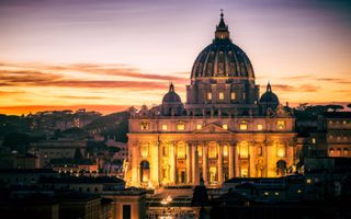 Uitzicht op de Sint-Pietersbasiliek in Vaticaanstad bij het vallen van de avond. beeld Getty Images