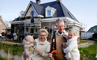 Theo en Jenny van der Linden met twee kleinkinderen voor hun nieuwbouwhuis in Brakel. „Veel dorpelingen houden de bouw in de gaten”, zegt Jenny. beeld Cor de Kock