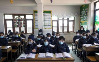 Schoolkinderen in Bkaktapur, Nepal, dragen een masker tegen besmetting met het coronavirus. Sinds de Napalese autoriteiten een besmetting met het virus constateerden in de stad Kathmandu zijn scholieren verplicht er één te dragen. beeld EPA, Narendra Shre