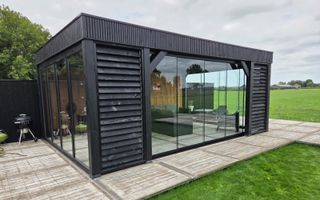 Een buitenverblijf met glazen schuifdeuren en uitzicht over weilanden