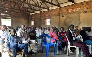 Tientallen Ugandese mannen zitten in een kerkzaal.