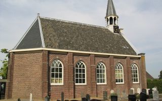 Oud kerkgebouw met torentje en grafstenen naast de kerk.