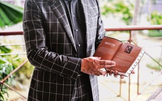 Wilfred Kols met een donkergrijs pak met een witte ruit heeft de Indonesische Bijbel vast