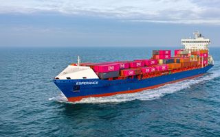 Een blauw schip geladen met zeecontainers vaart op volle zee.