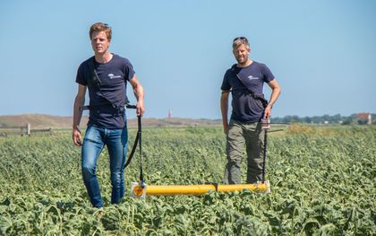 Twee werknemers van Acacia Water doen op Texel geofysische metingen om de kwaliteit van het grondwater te onderzoeken. Op de achtergrond de vuurtoren. beeld Tine te Winkel