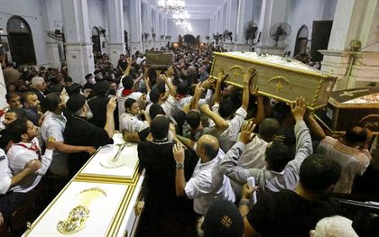 Kisten met overledenen worden de kerk ingedragen. beeld AFP, Khaled DESOUKI