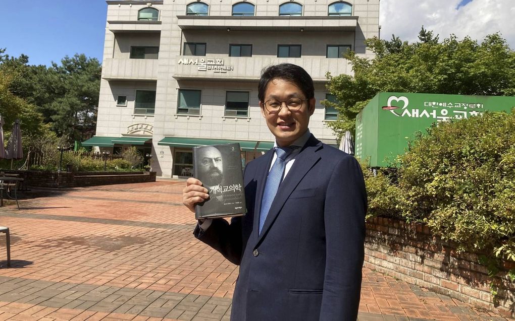 Changyun Choi voor zijn Saeseoul Church in Seoul. In zijn hand houdt hij de Koreaanse vertaling van een van de delen van de Gereformeerde Dogmatiek van Bavinck. beeld Changyn Choi