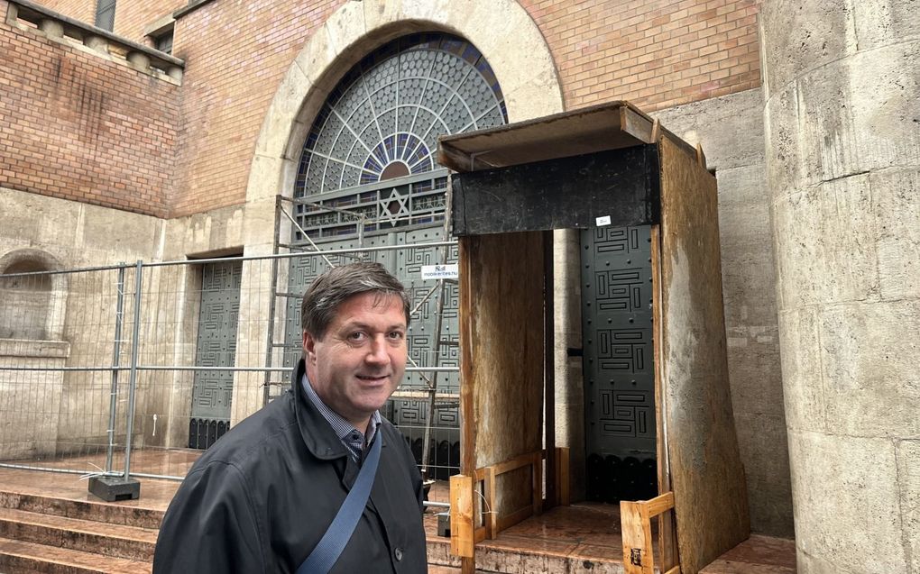 Ds. Imre Zöld voor de synagoge aan de Kazynczystraat in Boedapest. De hekken zijn er geplaatst vanwege een recente strijd tussen twee orthodox-Joodse groepen over de vraag wie de rechtmatige eigenaar van de synagoge is. beeld RD