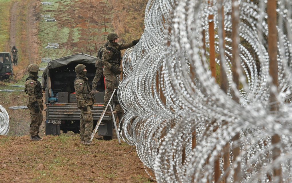 Militairen leggen een barrière aan van prikkeldraad op de grens van Polen, Rusland en Litouwen. Het hekwerk is bedoeld om illegale migranten, die door de Russen vanuit de Russische exclave Kaliningrad gefaciliteerd over de grens worden gedumpt, tegen te houden. beeld Bogdan Hrywniak