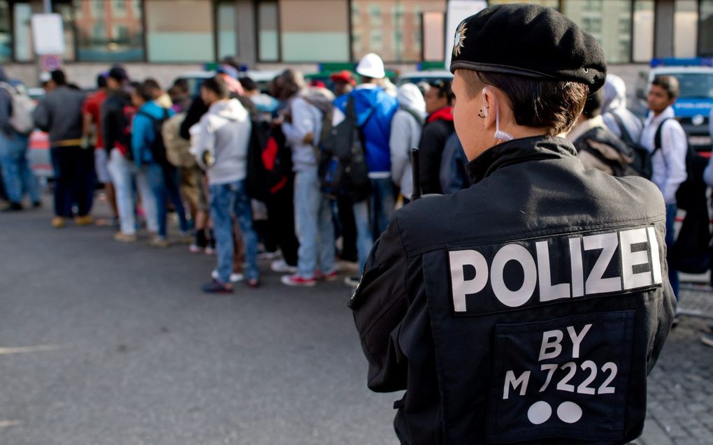 Een politieagent houdt in 2015 op het treinstation van de Duitse stad München toezicht op Syrische vluchtelingen die op de bus worden gezet. beeld EPA, Sven Hoppe