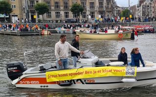Motorbootje met vier inzittenden vaart op het water met een spandoek met de tekst: Jezus komt spoedig! Ben je er klaar voor? 