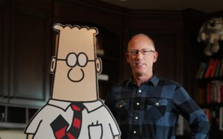 Een man van middelbare leeftijd staat naast een levensgroot kartonnen stripfiguur.