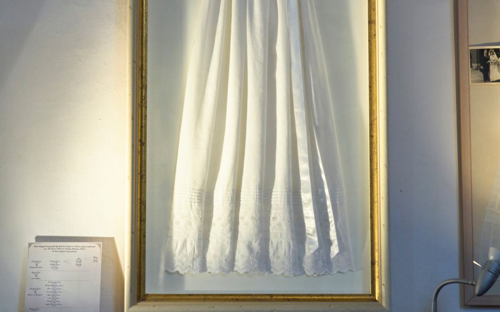 Een doopjurk aan een wand.