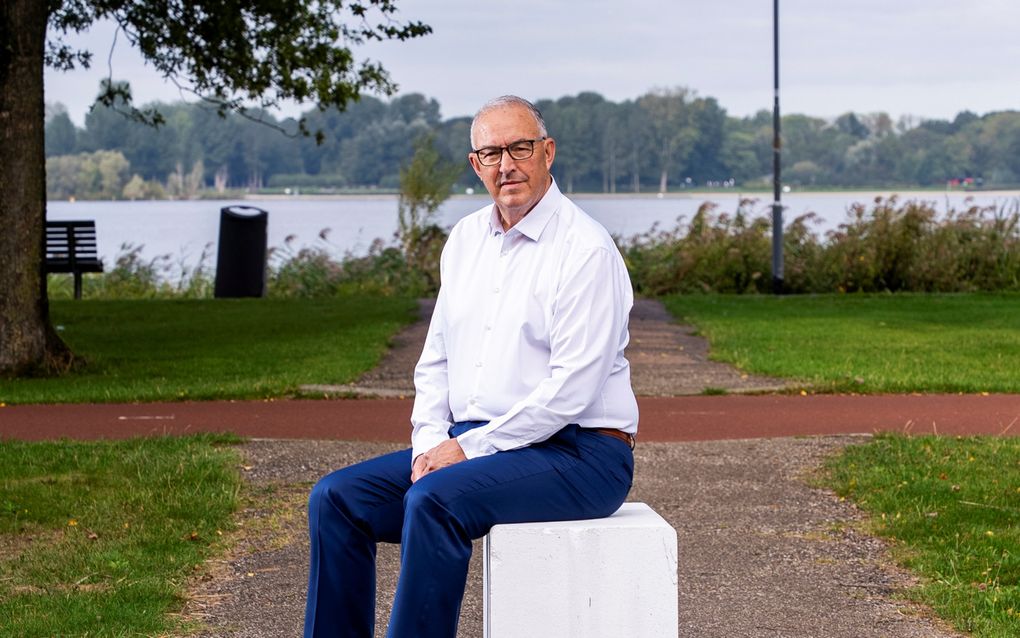 Man zit op een wit bankje voor het water.