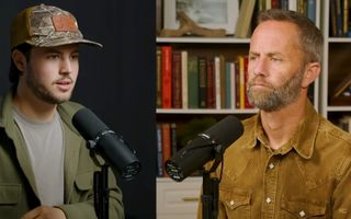 Twee mannen spreken achter een microfoon.