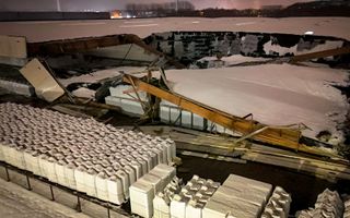 Een grote hal met een ingestort dak waar de witte sneeuw nog op ligt.