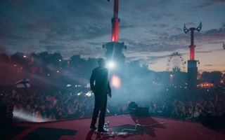 Een jonge man staat in pak op een podium.