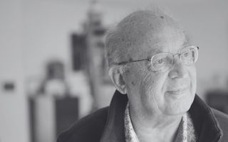 Zwart-wit foto van een oudere man met vrijwel kaal hoofd en bril.