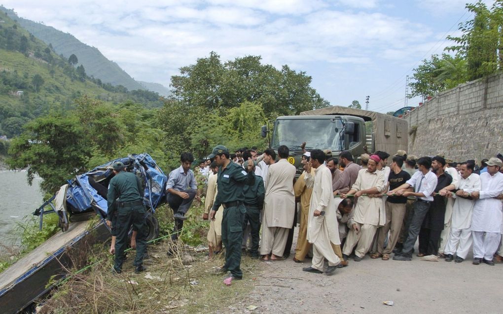 Het wrak van de bus wordt uit het water getrokken in Muzaffarabad. Foto EPA