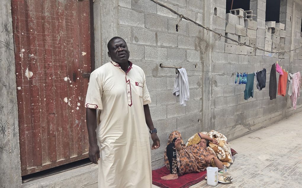 Man in licht gewaad staat voor een half afgebouwd gebouw. 